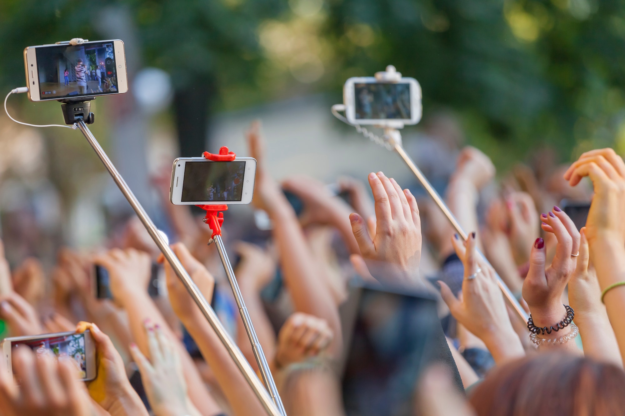 Social media at the concert, phones on selfie sticks